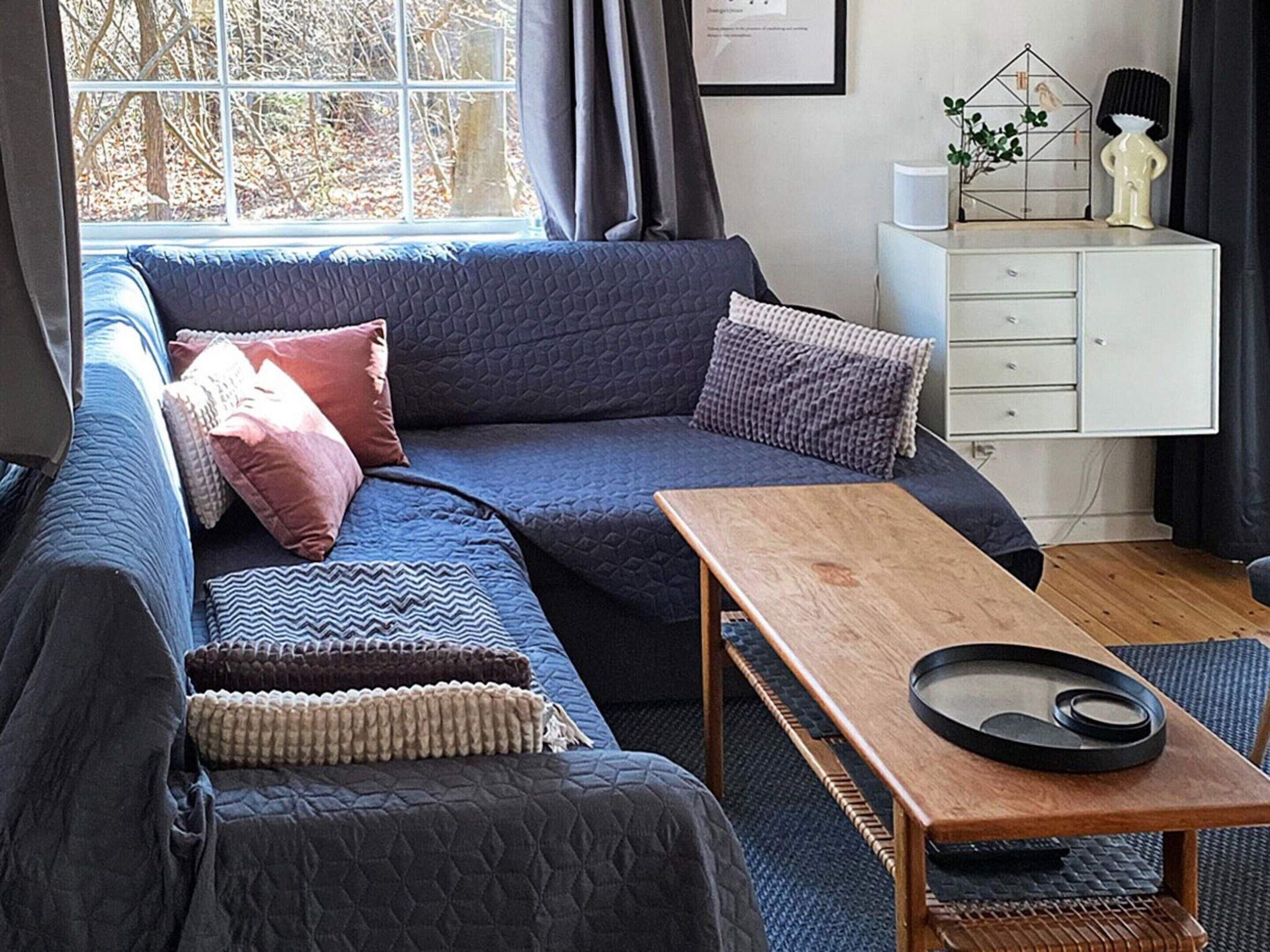 Una sala acogedora con un sofá azul, una mesa de centro de madera y un armario blanco.