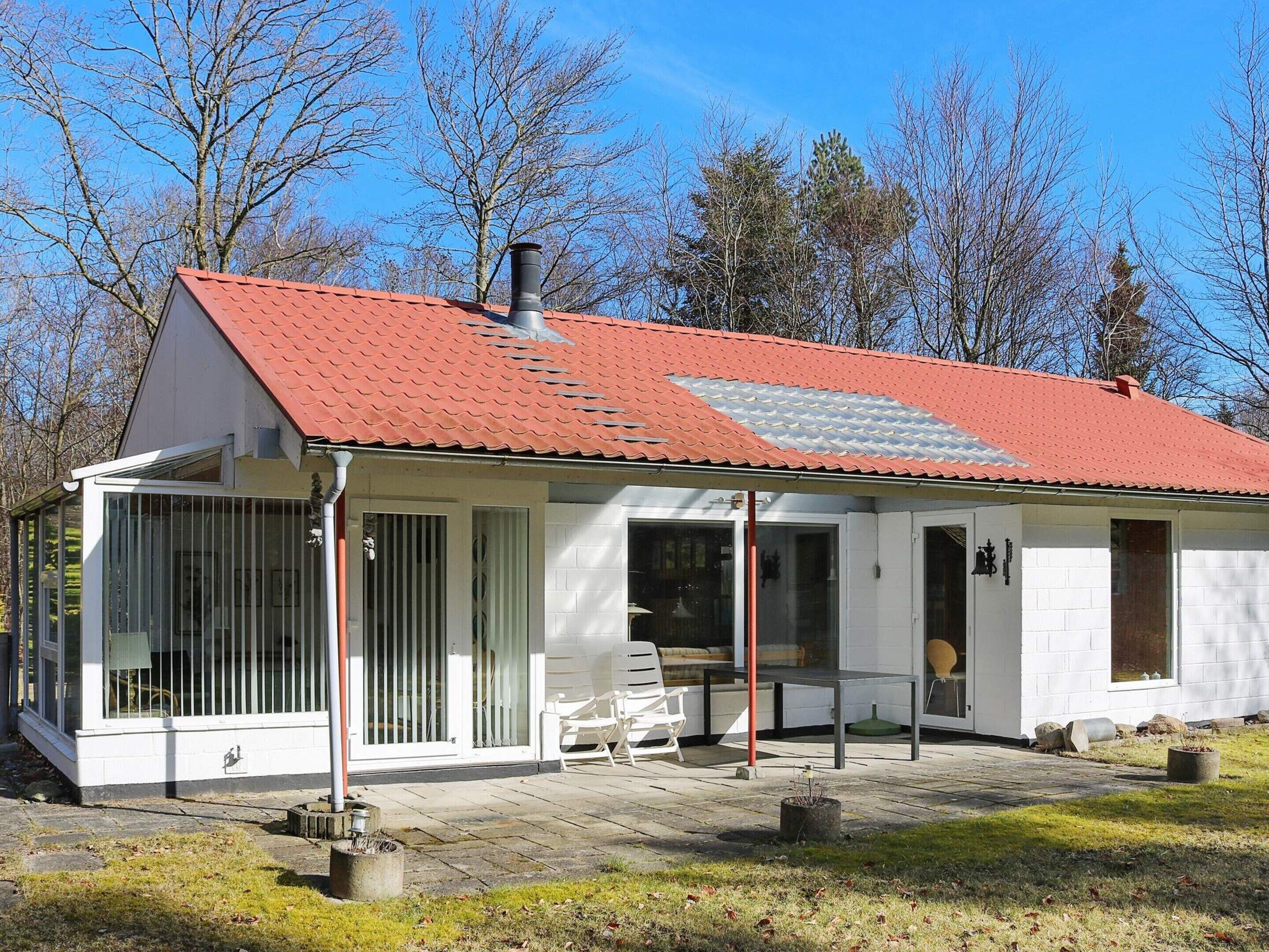 A single-story house with a red-tiled roof, large windows, and a covered porch area.