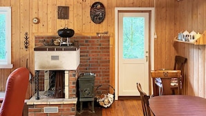 A cozy room with a brick fireplace, a dining table, and a wooden floor. - 4 Person Holiday Home in Reksteren (Tysnes)