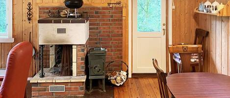Una habitación acogedora con chimenea de ladrillo, una mesa de comedor y suelo de madera.