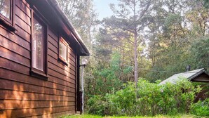 A wooden cabin with a window, surrounded by dense greenery and trees. - 4 Person Holiday Home in Reksteren (Tysnes)