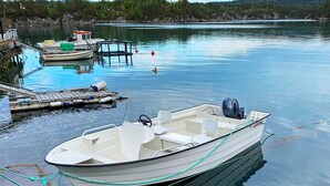 A small, motorboat docked at a calm lake with a dock and another boat in the background. - 4 Person Holiday Home in Reksteren (Tysnes)