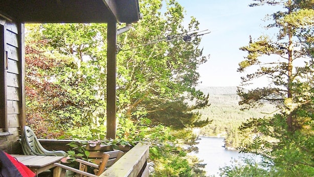 A wooden deck with a view of a forest and a lake. - 4 Person Holiday Home in Reksteren (Tysnes)