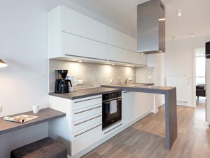 A modern kitchen with white cabinetry, a built-in oven, and a coffee maker. - 5 Star Holiday Home in Wendtorf (Wendtorf)
