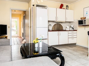A modern kitchen with white cabinets, a black countertop, and a tiled floor.