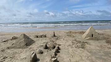 A sandy beach with several sand sculptures and a pyramid structure.