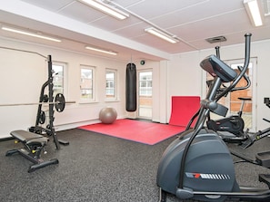 A gym with exercise equipment, a punching bag, and a red mat.