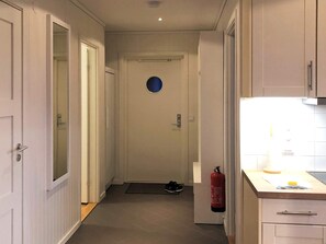 A narrow hallway leading to a door with a circular cut-out, a fire extinguisher mounted on the wall, and a small rug on the floor. - 4 Star Holiday Home in Salen (Salen)