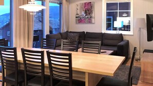 A dining area with a wooden table and chairs, a sofa, and a window with curtains. - 4 Star Holiday Home in Salen (Salen)