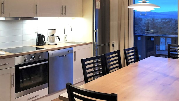 A modern kitchen with a built-in oven, dishwasher, and a dining area with a wooden table and chairs. - 4 Star Holiday Home in Salen (Salen)