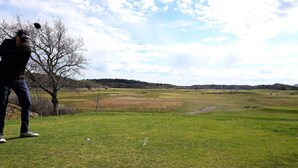 A golf course with a person preparing to hit a golf ball, trees, and a clear sky. - 4 Star Holiday Home in Salen (Salen)