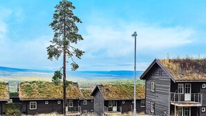 Filas de cabañas con techo de hierba, un árbol alto y una vista despejada del paisaje.
