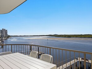 Eine Terrasse mit Tisch und Stühlen mit Blick auf einen Fluss und eine Stadtlandschaft im Hintergrund.