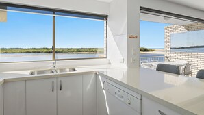 Une cuisine moderne dotée d’une grande fenêtre, d’un lave-vaisselle Bosch et offrant une vue sur la plage.
