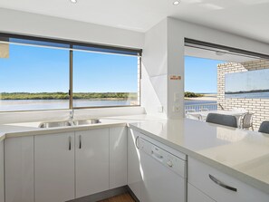 Eine moderne Küche mit großem Fenster, einem Geschirrspüler von Bosch und Blick auf den Strand.