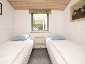 A room with two single beds, a window with a view, a radiator, and a painting on the wall. - 8 Person Holiday Home in Laeso (Læsø)