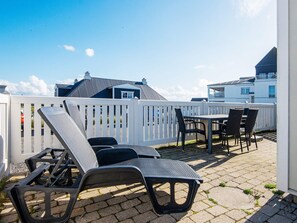 En patio med loungesenge og et bord, omgivet af et hvidt hegn.