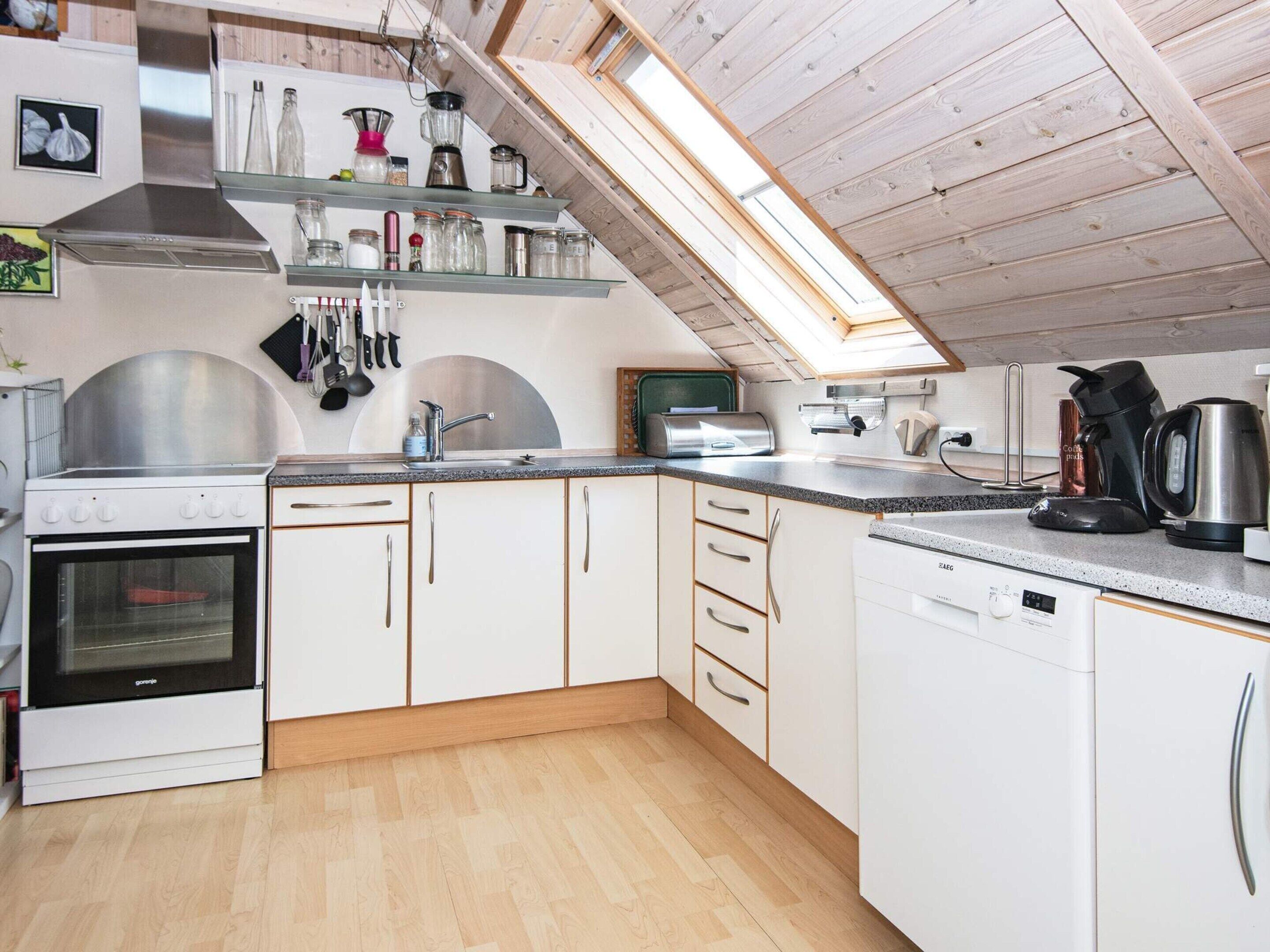 A modern kitchen with white cabinets, a stainless steel stove, and a skylight.