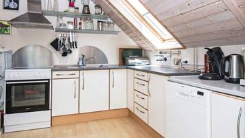 A modern kitchen with white cabinets, a stainless steel stove, and a skylight.