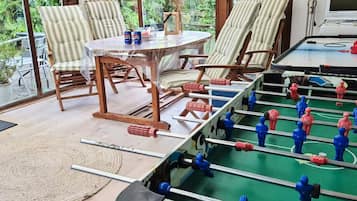 A room with a foosball table, striped chairs, a table with cans, and a TV.