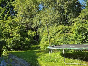 A trampoline in a grassy area with trees in the background.