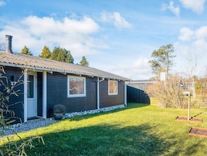 A single-story house with a dark exterior, a chimney, and a well-maintained lawn. - 4 Star Holiday Home in Grenaa (Grenaa)