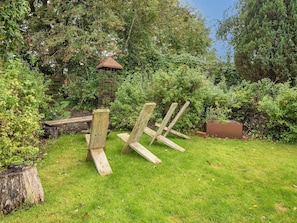 A garden with a wooden bench, a bird feeder, and a small wooden structure. - 4 Star Holiday Home in Grenaa (Grenaa)