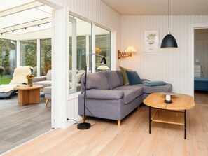 A modern living room with a grey sofa, a round wooden coffee table, and a black pendant light. - 4 Star Holiday Home in Grenaa (Grenaa)