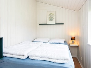 Une chambre à coucher avec un lit, des oreillers, une table de chevet avec une lampe et un tableau encadré au mur.