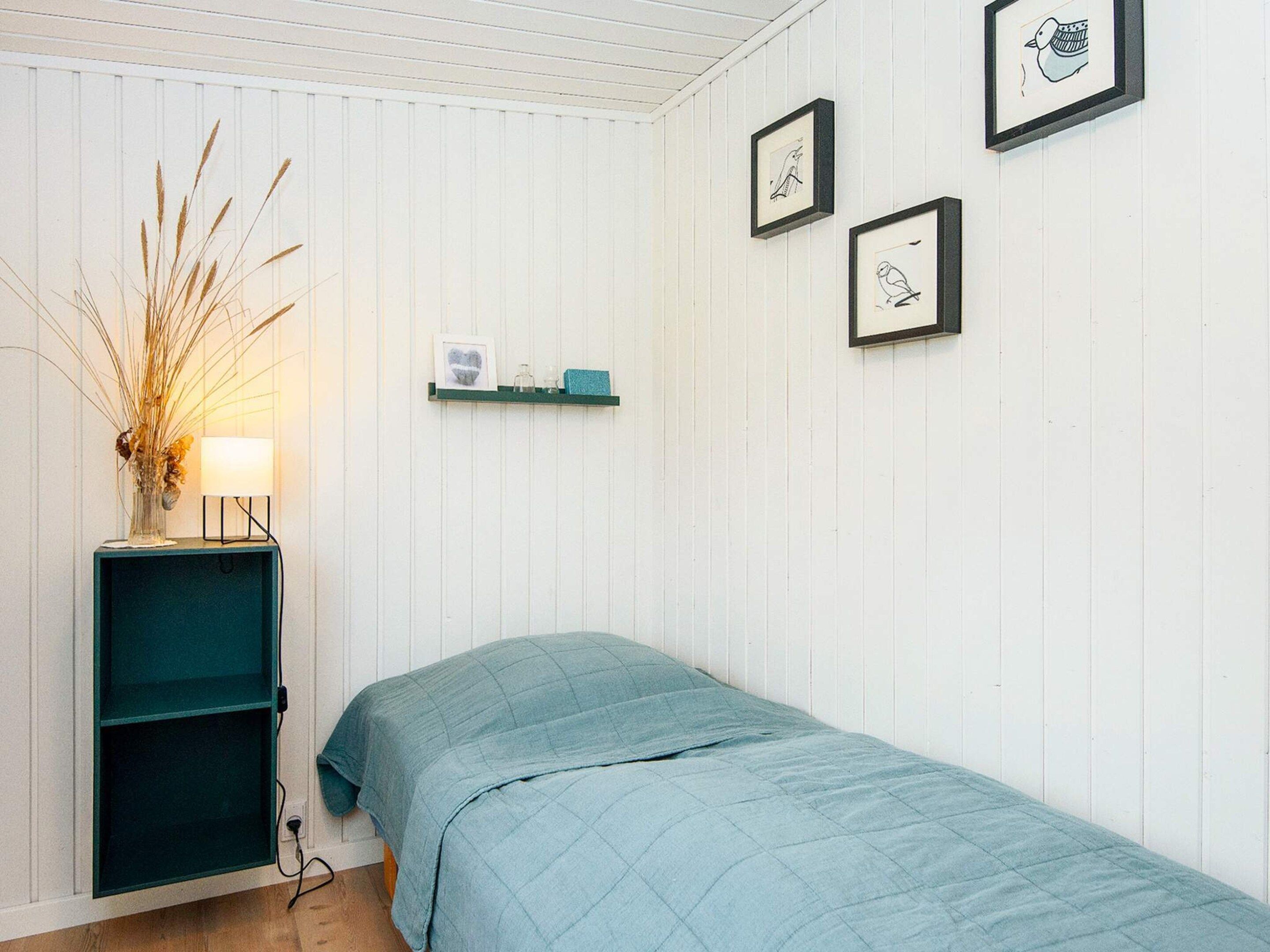 Une pièce comprenant un lit, une étagère avec des objets décoratifs et des tableaux encadrés accrochés au mur.