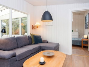 Un salon moderne avec un canapé gris, une table basse en bois et une suspension noire.