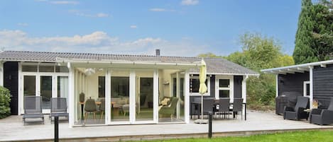 Une maison dotée d’un patio couvert, d’un espace salon extérieur et d’une pelouse.