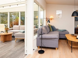 Un salon moderne avec un canapé d’angle gris, une table basse en bois et un lampadaire.