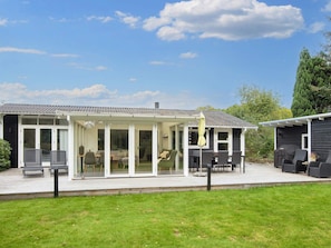Une maison dotée d’un patio couvert, d’un espace salon extérieur et d’une pelouse.