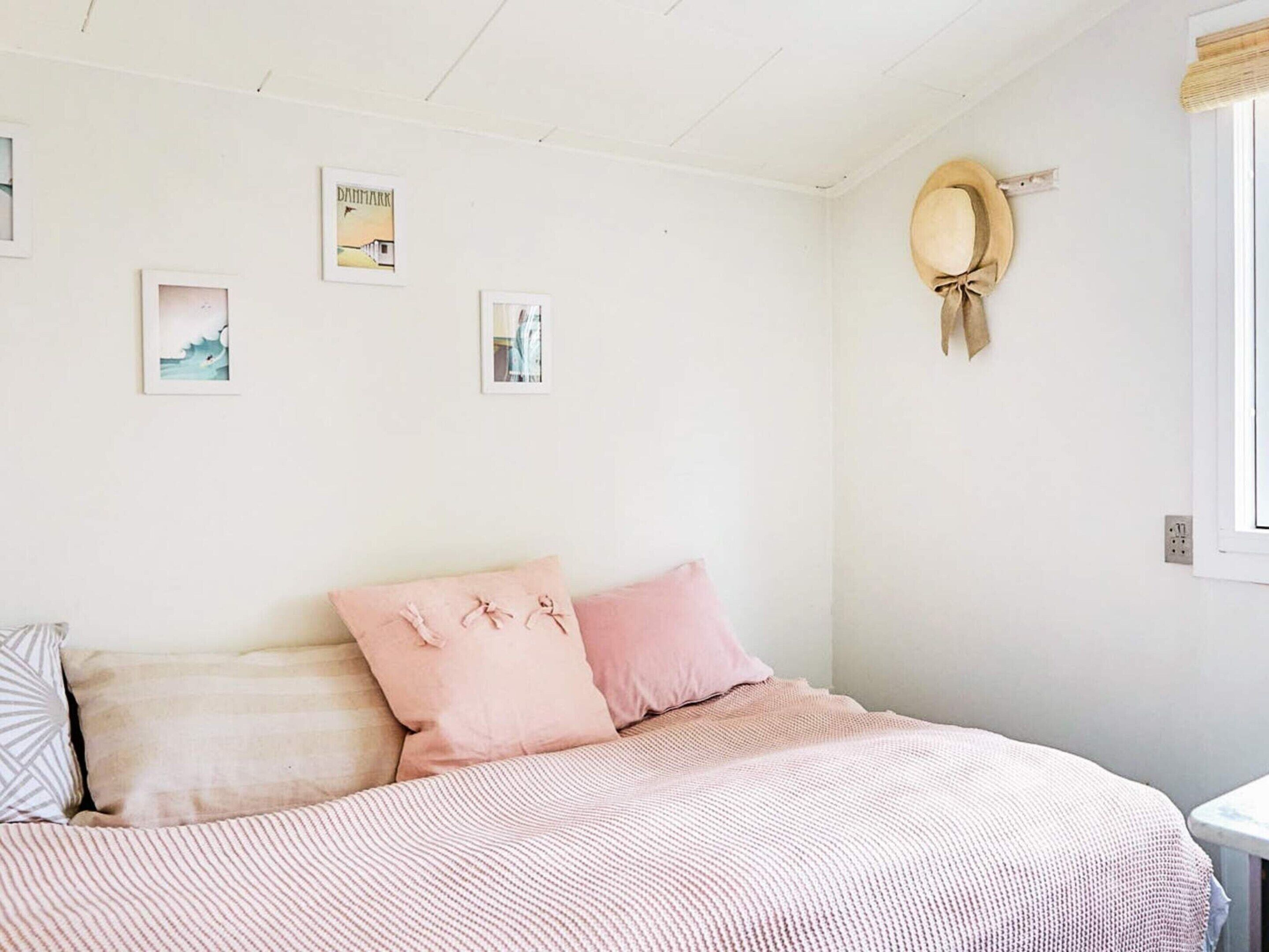 A bedroom with a bed, pillows, and wall art.