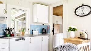 Eine moderne Küche mit weißen Schränken, einer Spüle und einer Uhr an der Wand.