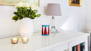 Ein weißes Regal mit einer Vase weißer Rosen, einer Lampe und zwei Kerzenständern.