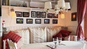 Ein gemütlicher Essbereich mit einem runden Tisch, weißen Stühlen und einer Bank mit gestreiften Kissen.