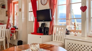 Ein gemütliches Zimmer mit Holztisch, Fernseher und einer Wanduhr.