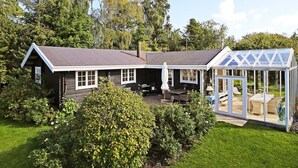 A house with a large glass greenhouse, a covered patio, and a well-maintained lawn. - 4 Star Holiday Home in Graested (Graested)