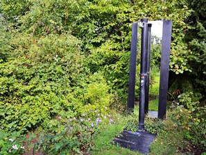 Une structure métallique noire à la base plate, entourée d’un feuillage vert et dense.