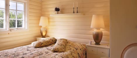 A bedroom with a bed, two bedside lamps, a nightstand, a dresser, and a chair.