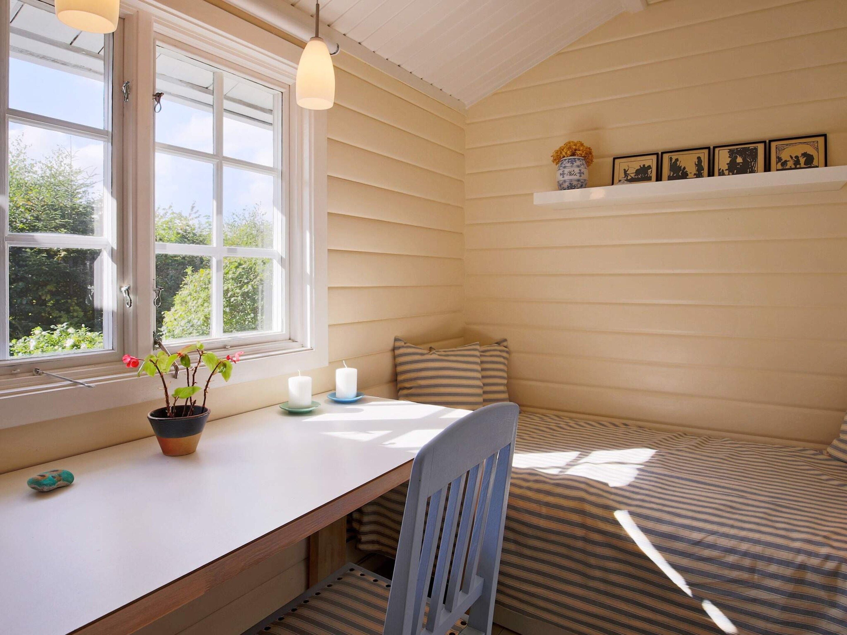 A cozy room with a window, a desk, a chair, and a bed.