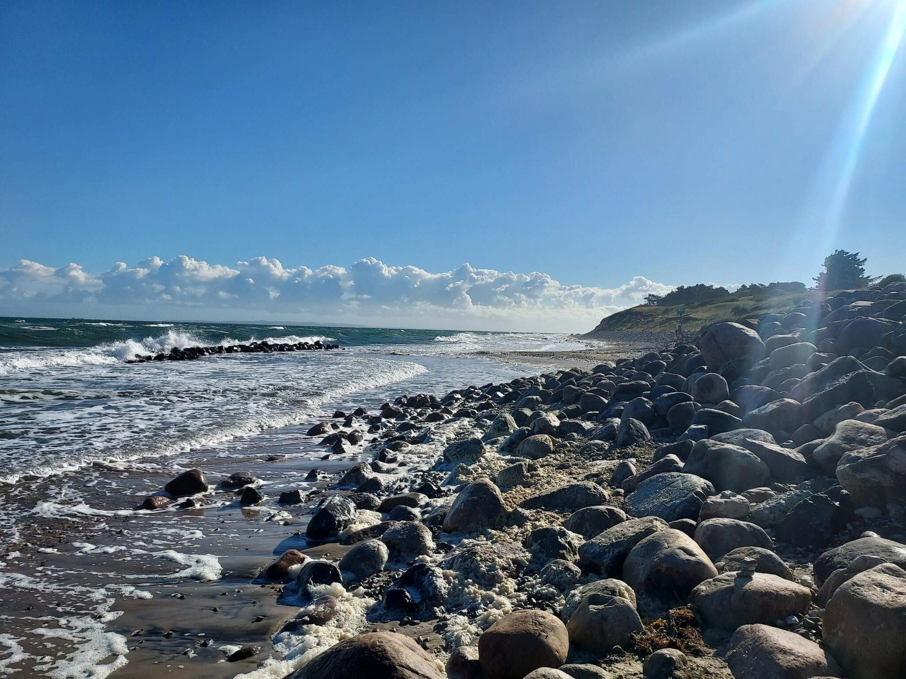 Ein felsiger Strand mit brechenden Wellen.