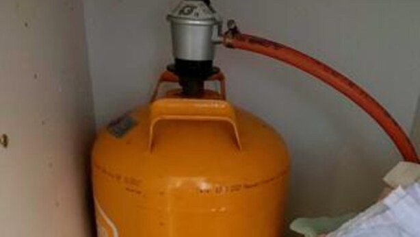 A large orange gas cylinder with a red hose attached, positioned against a wall. - 4 Star Holiday Home in Graested (Graested)