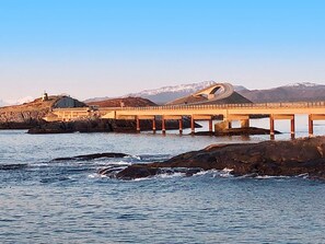 A bridge with a unique arch design over a body of water, with mountains in the background. - 6 Person Holiday Home in Averoy (Averoy)
