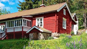 A red wooden house with white trim, a stone foundation, and a porch with white railings. - 7 Person Holiday Home in Jarbo-by Traum (Jarbo)