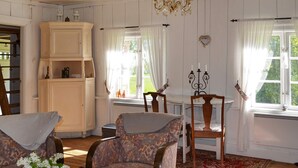 A cozy room with a wooden floor, patterned armchairs, a white cabinet, and a red rug. - 7 Person Holiday Home in Jarbo-by Traum (Jarbo)