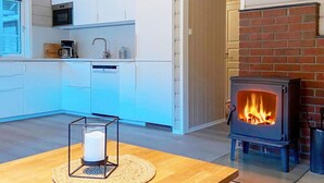 A modern kitchen with white cabinets, a microwave, and a small stove with a visible fire. - 4 Star Holiday Home in Jorpeland (Strand)