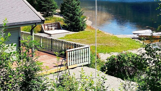 A lakeside property with a wooden deck, a flagpole, and a view of the lake. - 4 Star Holiday Home in Jorpeland (Strand)